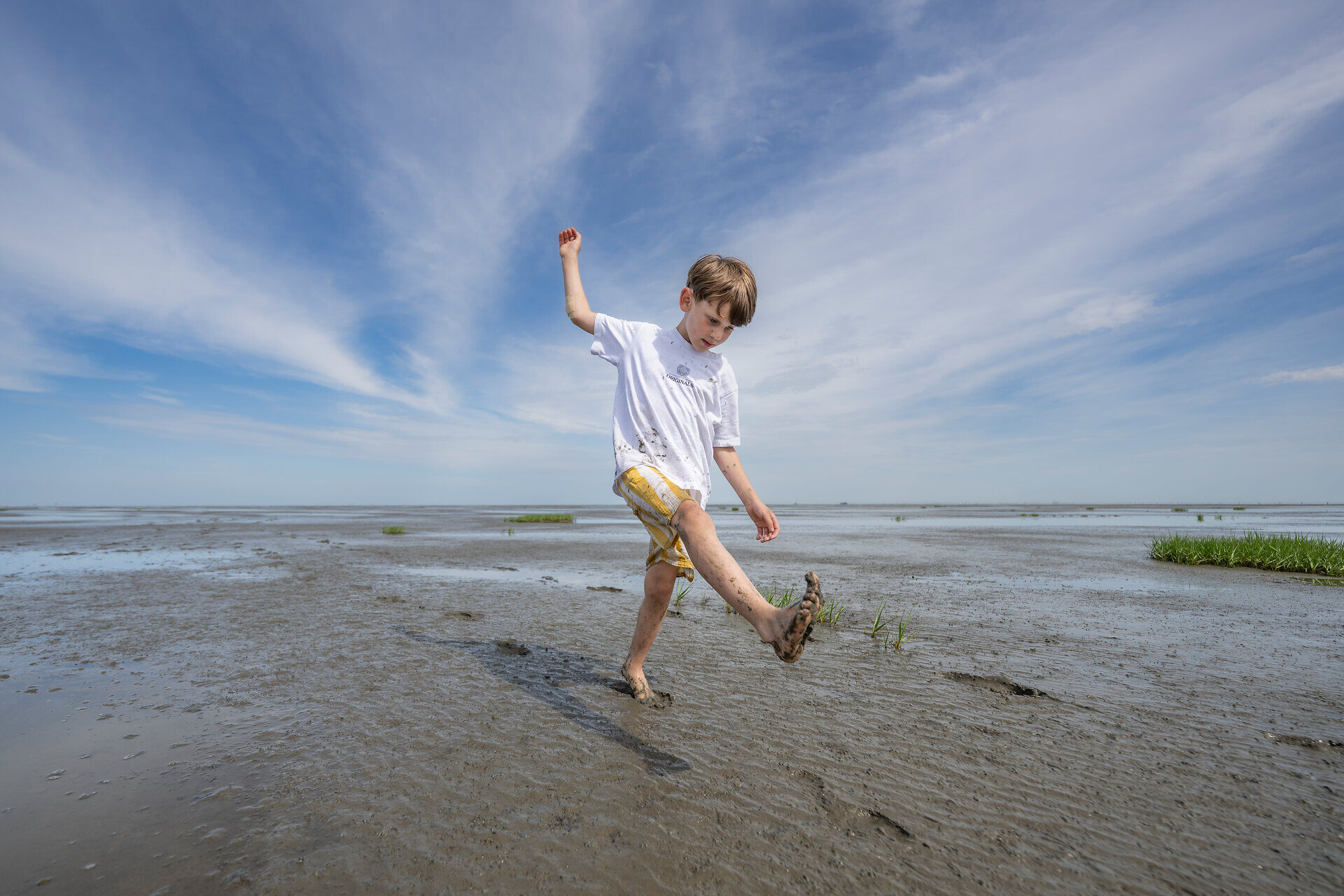 Kinder spielen barfuss im Wattenmeer